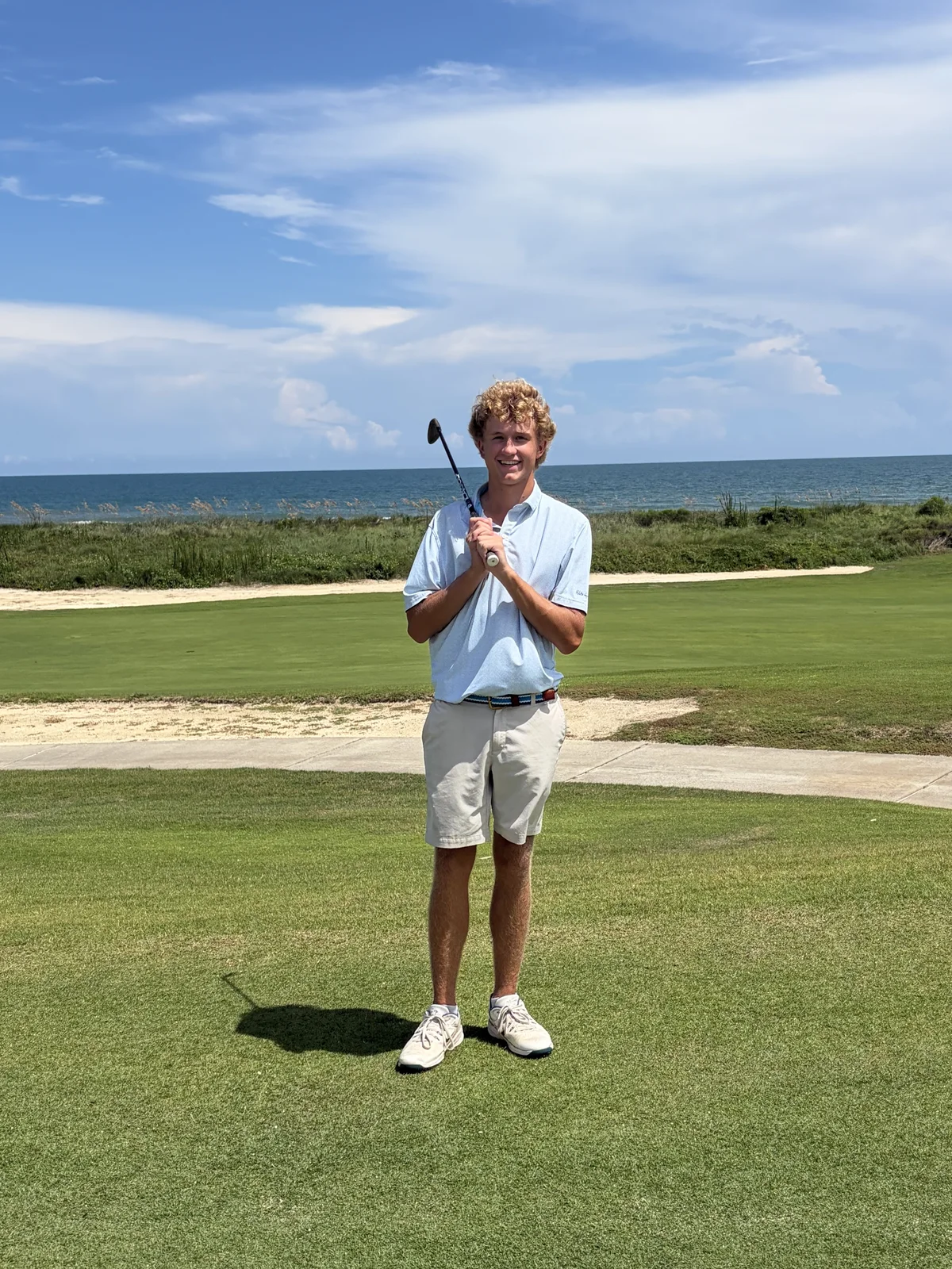 Peter Sirianni holding a golf club on a coastal golf course